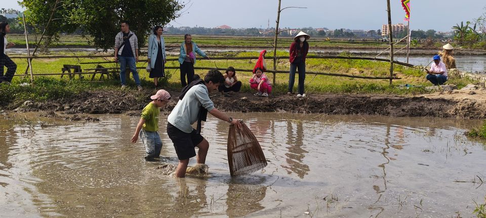 Ở một góc khác, các du khách hào hứng tham gia bắt cá dưới bùn.